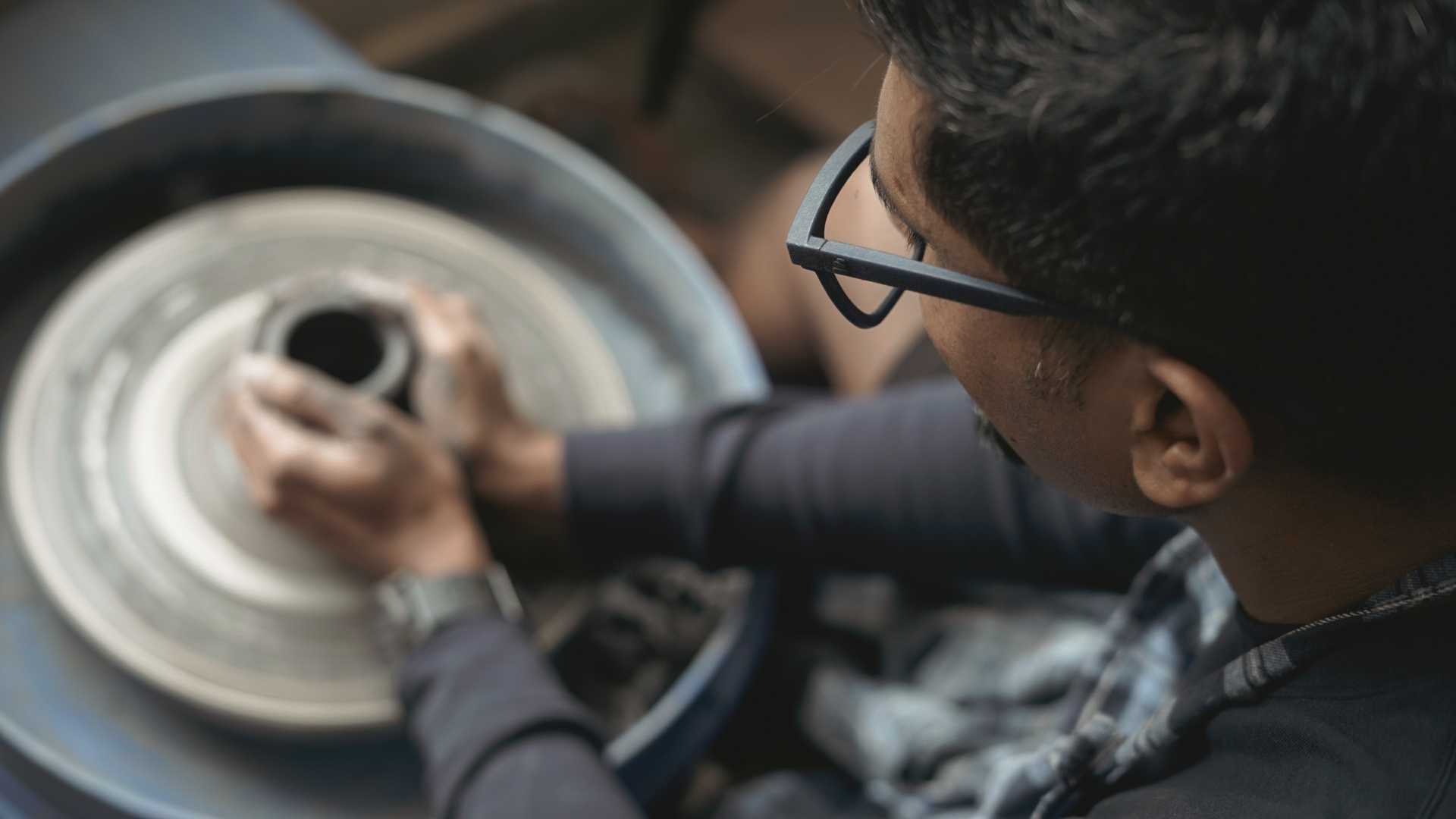 A student shaping a vessel on the pottery wheel