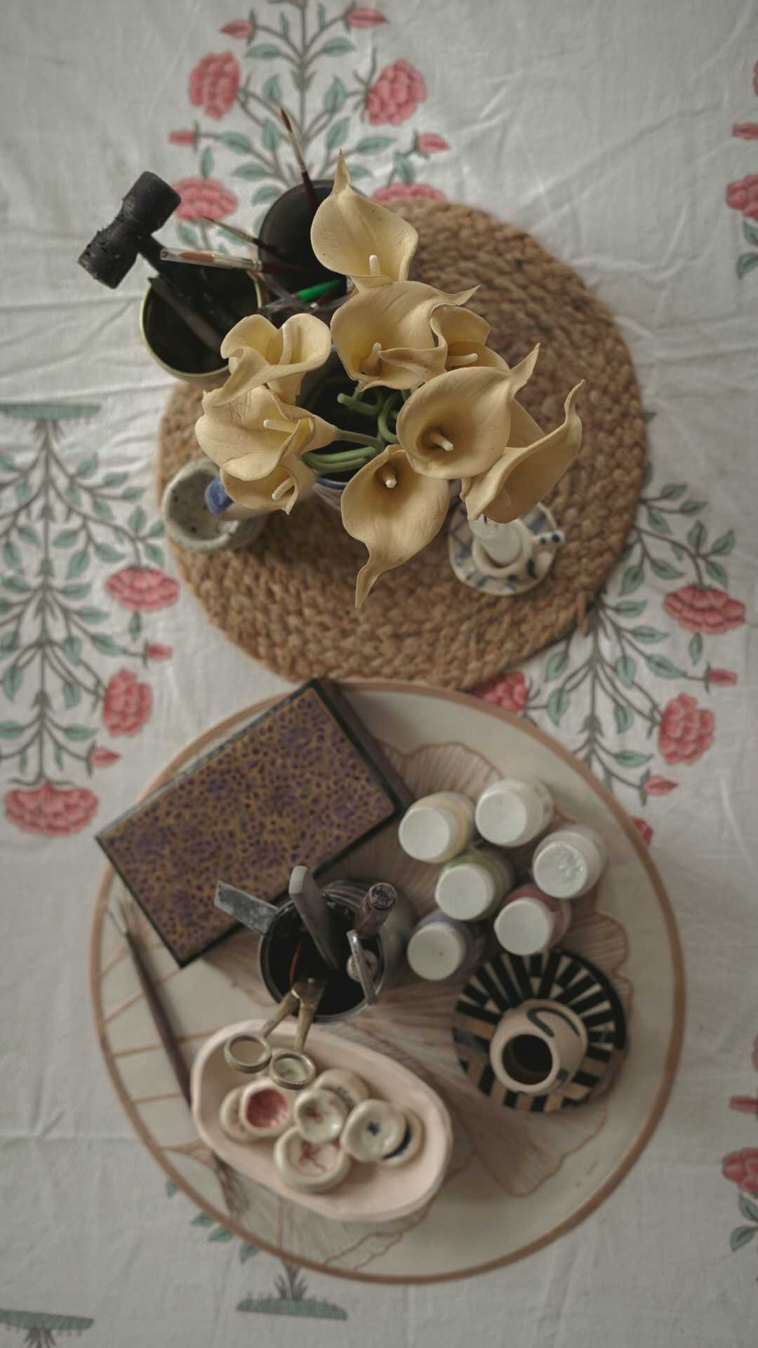 Overhead flat-lay of paint bottles, brushes, a mixing palette and a freshly painted striped mug