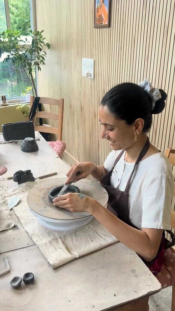 A guest burnishing the rim of a dark clay dish smooth