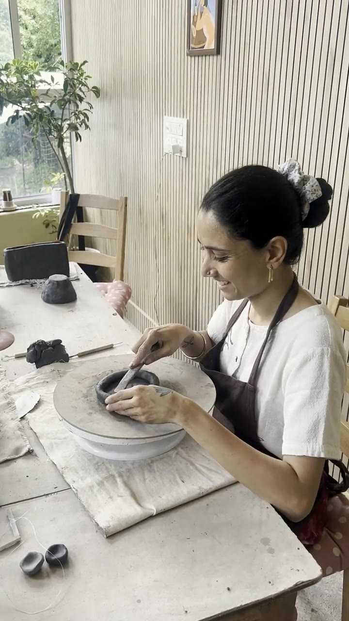 Burnishing the rim of a small dark bowl with a wooden rib
