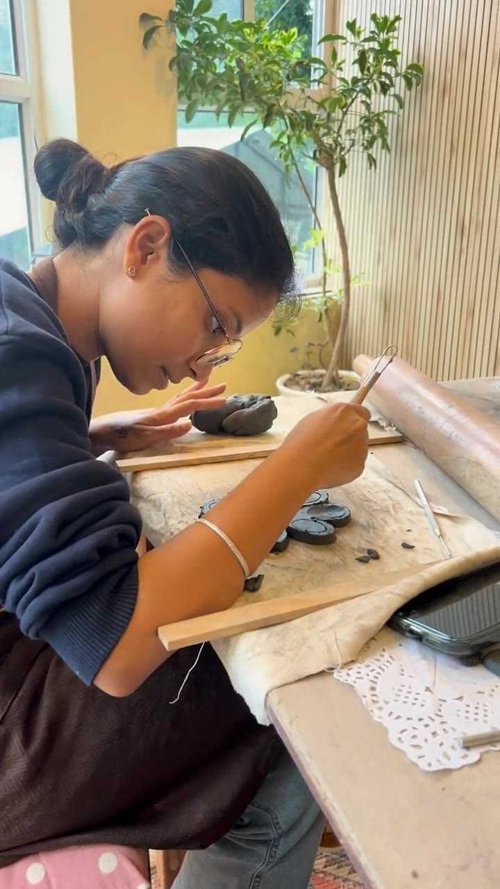 A guest carving fine detail into a small clay piece at the window table