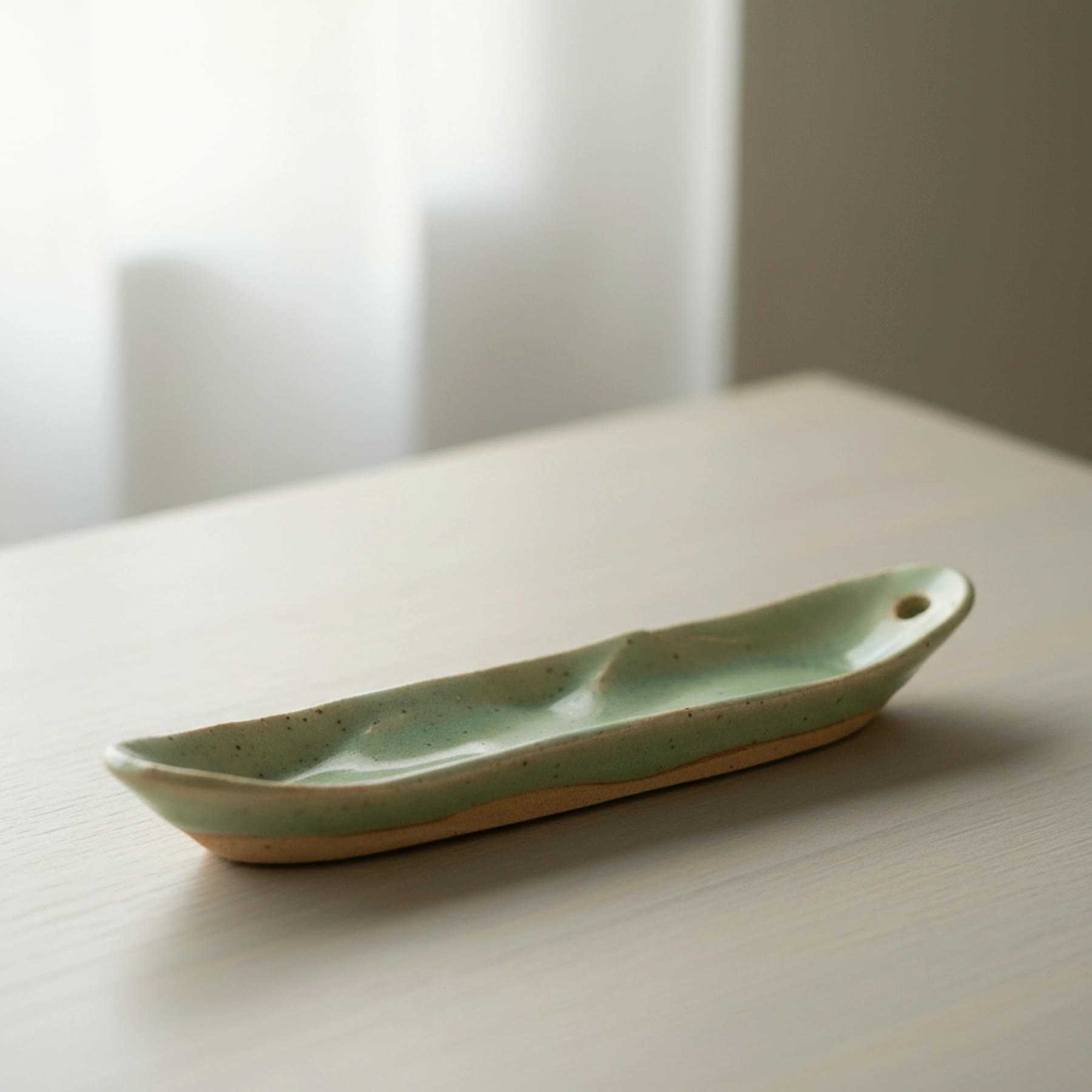 Illustration of a long, narrow celadon ceramic ash catcher for incense sticks