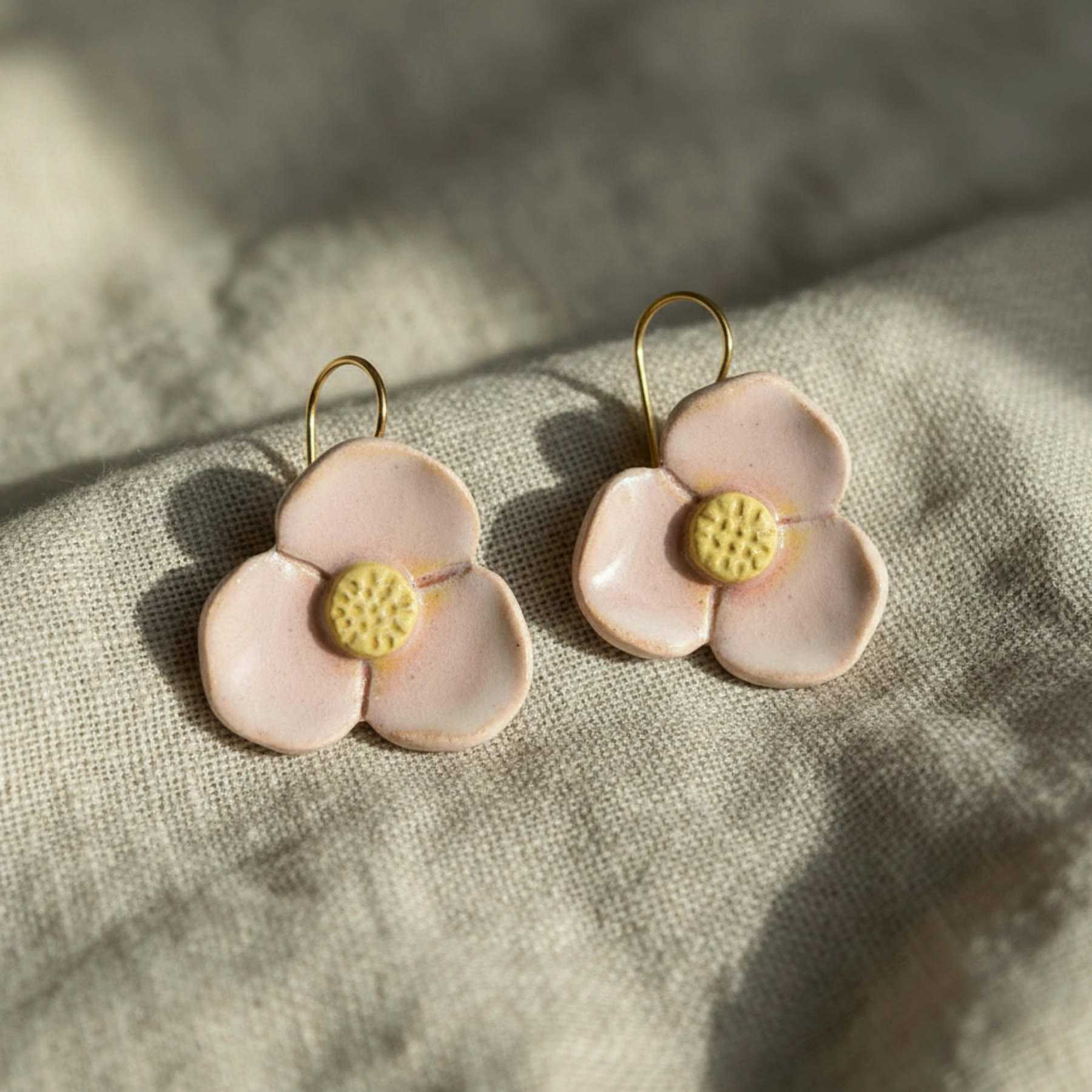Illustration of pink flower-shaped ceramic drop earrings on gold hooks