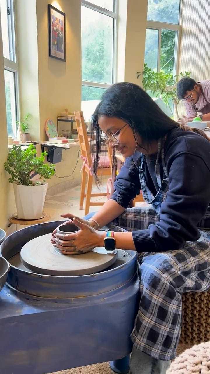 A guest smiling at the pottery wheel with the valley visible through the window
