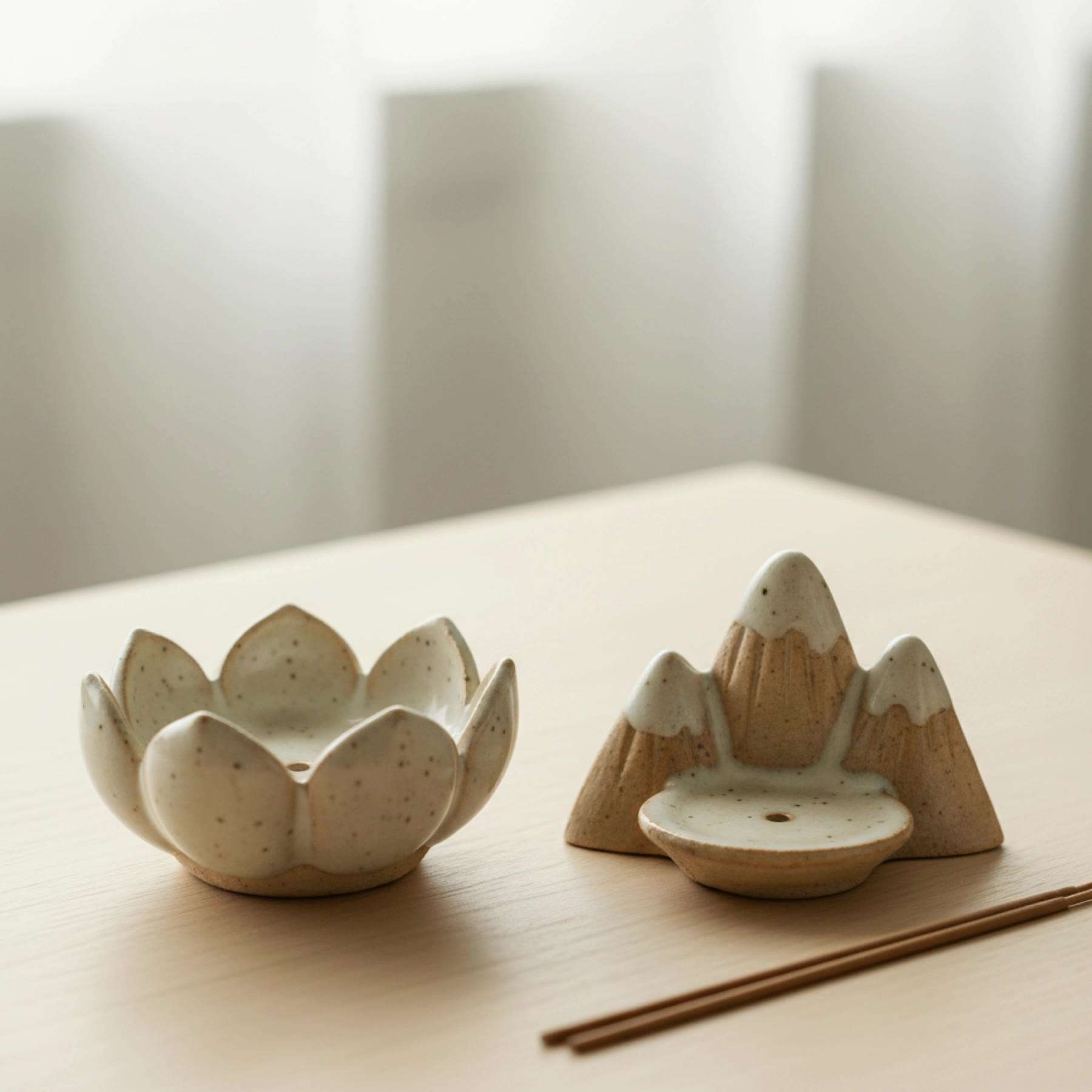 Illustration of two small ceramic incense holders, a lotus and a mountain