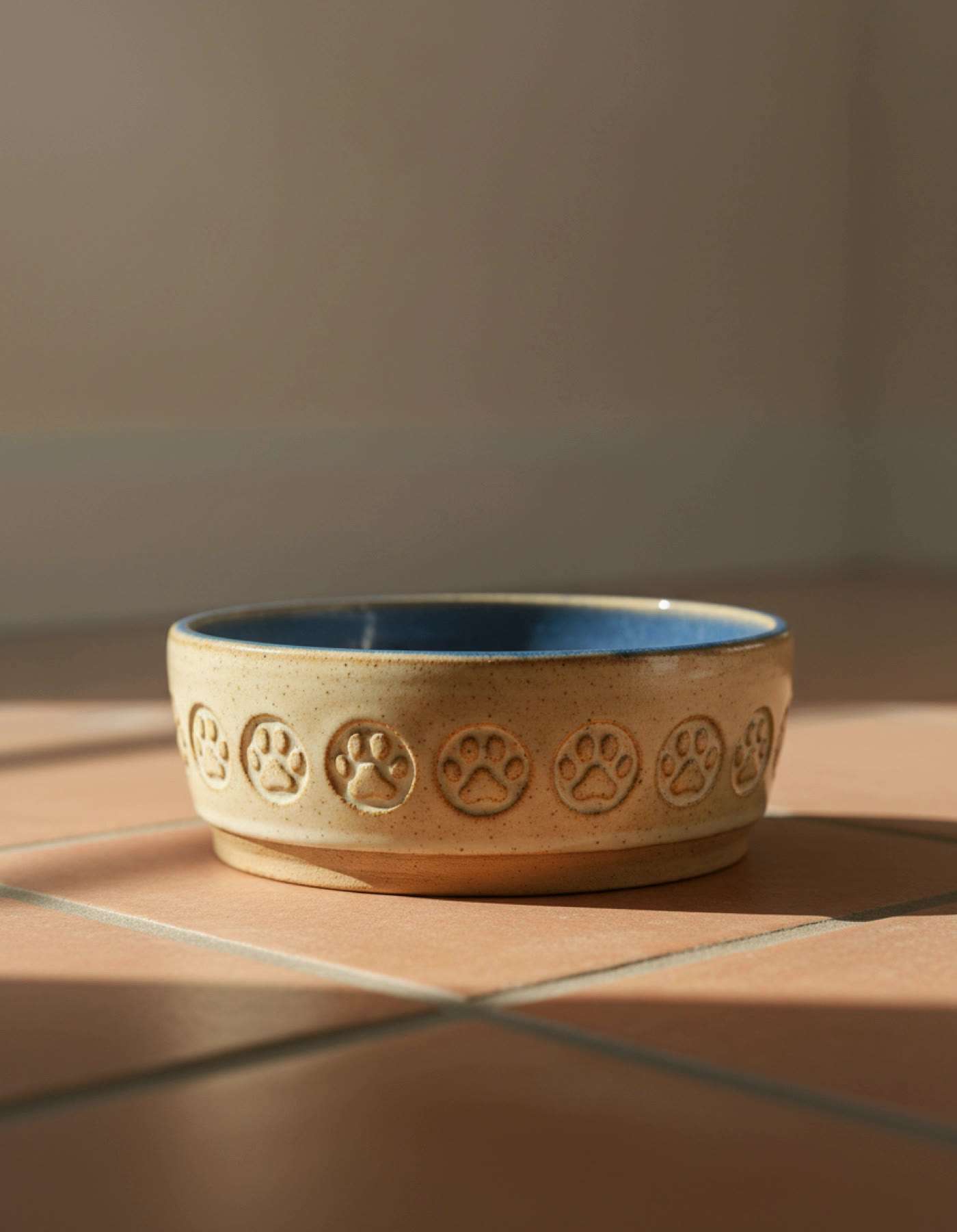 Illustration of a heavy cream pet bowl with paw prints pressed around the side and a blue inside