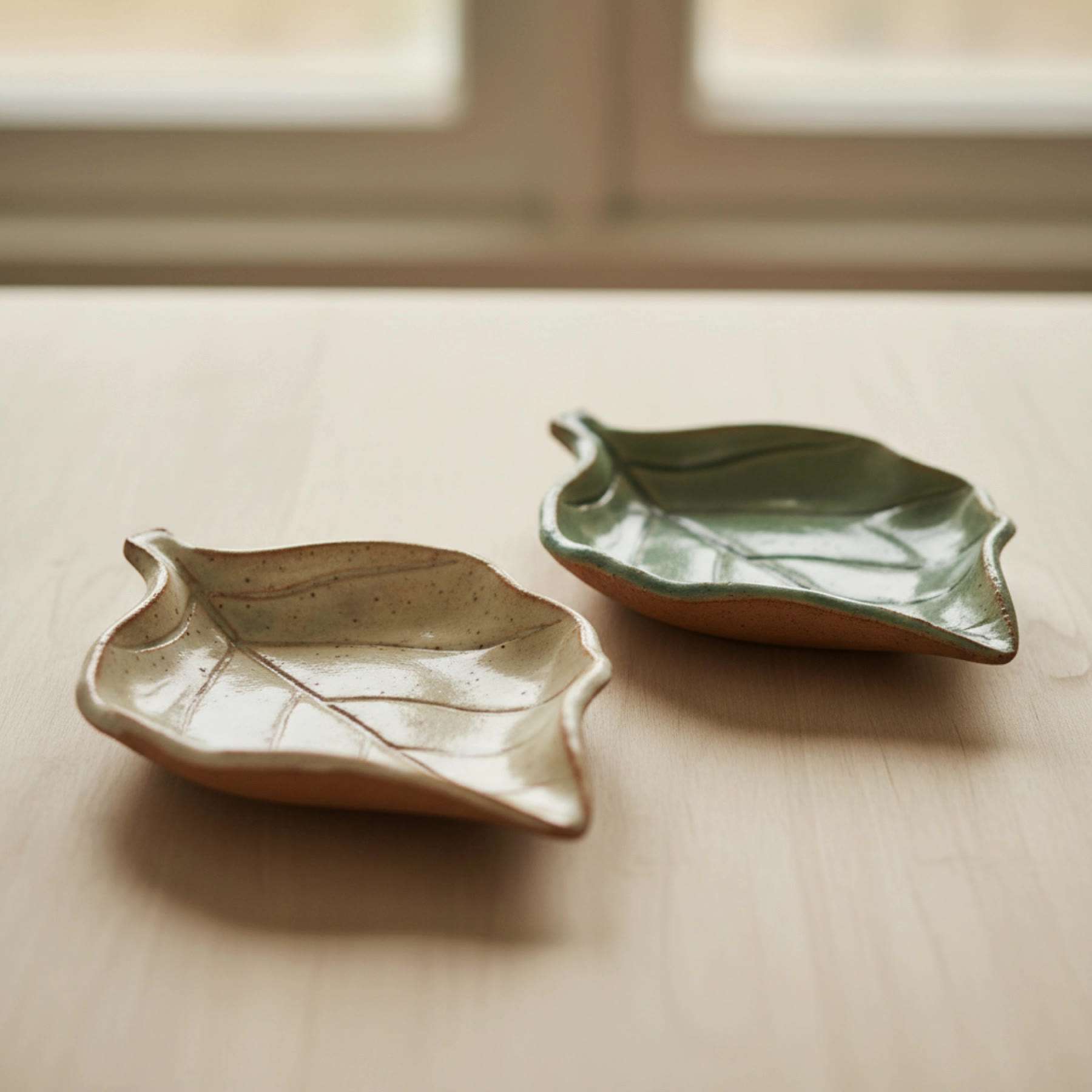 Illustration of two leaf-shaped ceramic spoon rests, green and cream