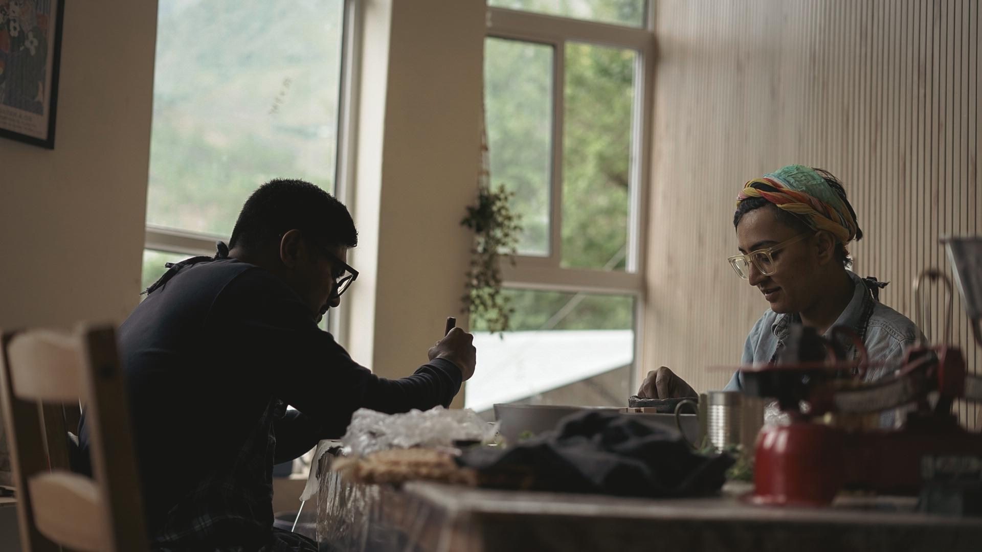 Two artists hand-building at communal table with mountain view