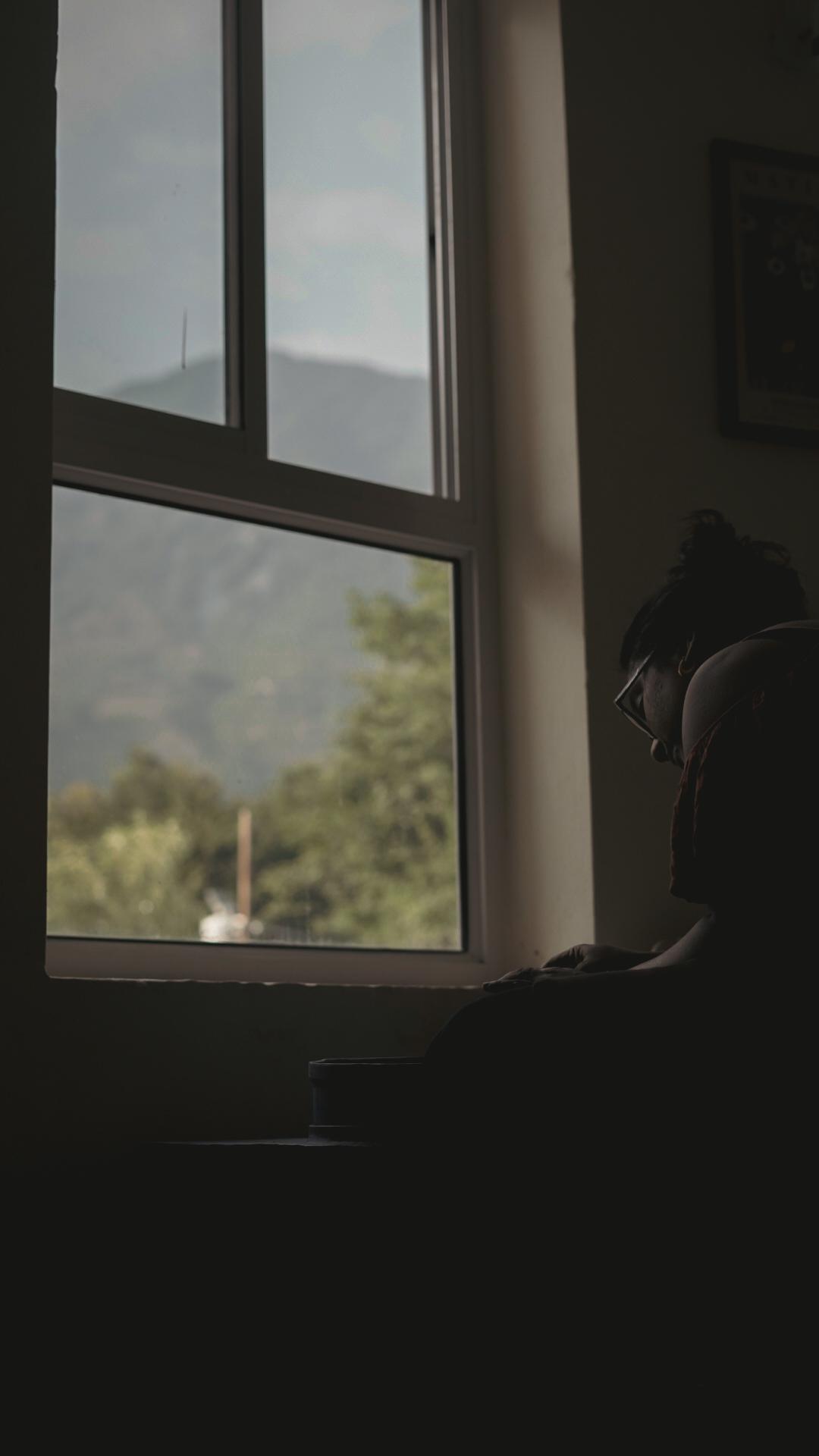 Potter in silhouette with misty Dhauladhar range outside