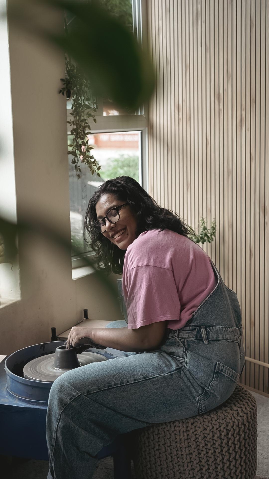 Mita smiling at the wheel with clay-covered hands