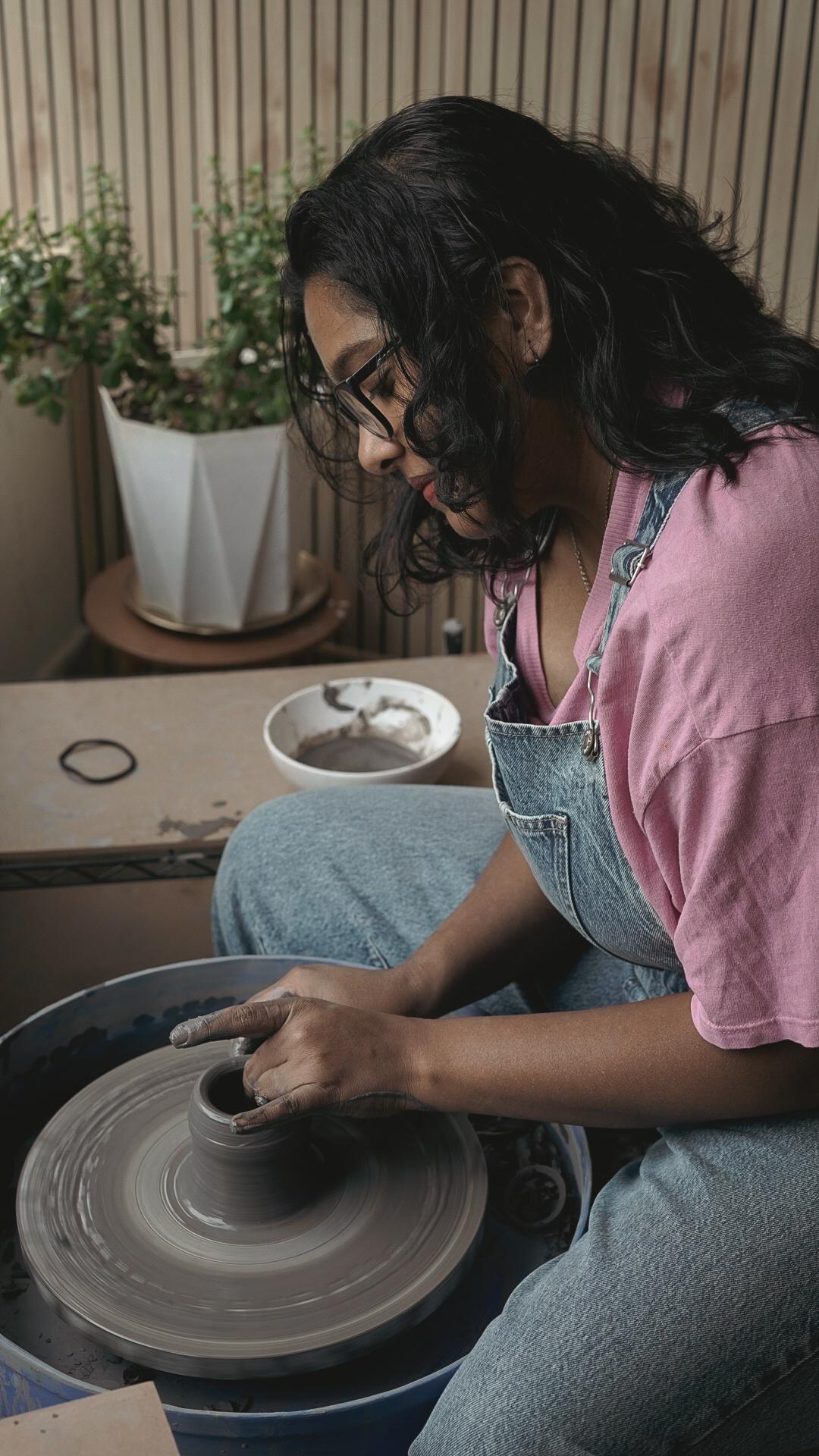 Focused potter shaping clay with wooden slat wall behind