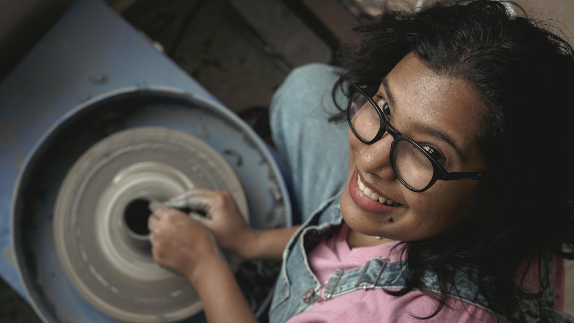Mita smiling up from the pottery wheel — a face you wouldn't find in a boardroom