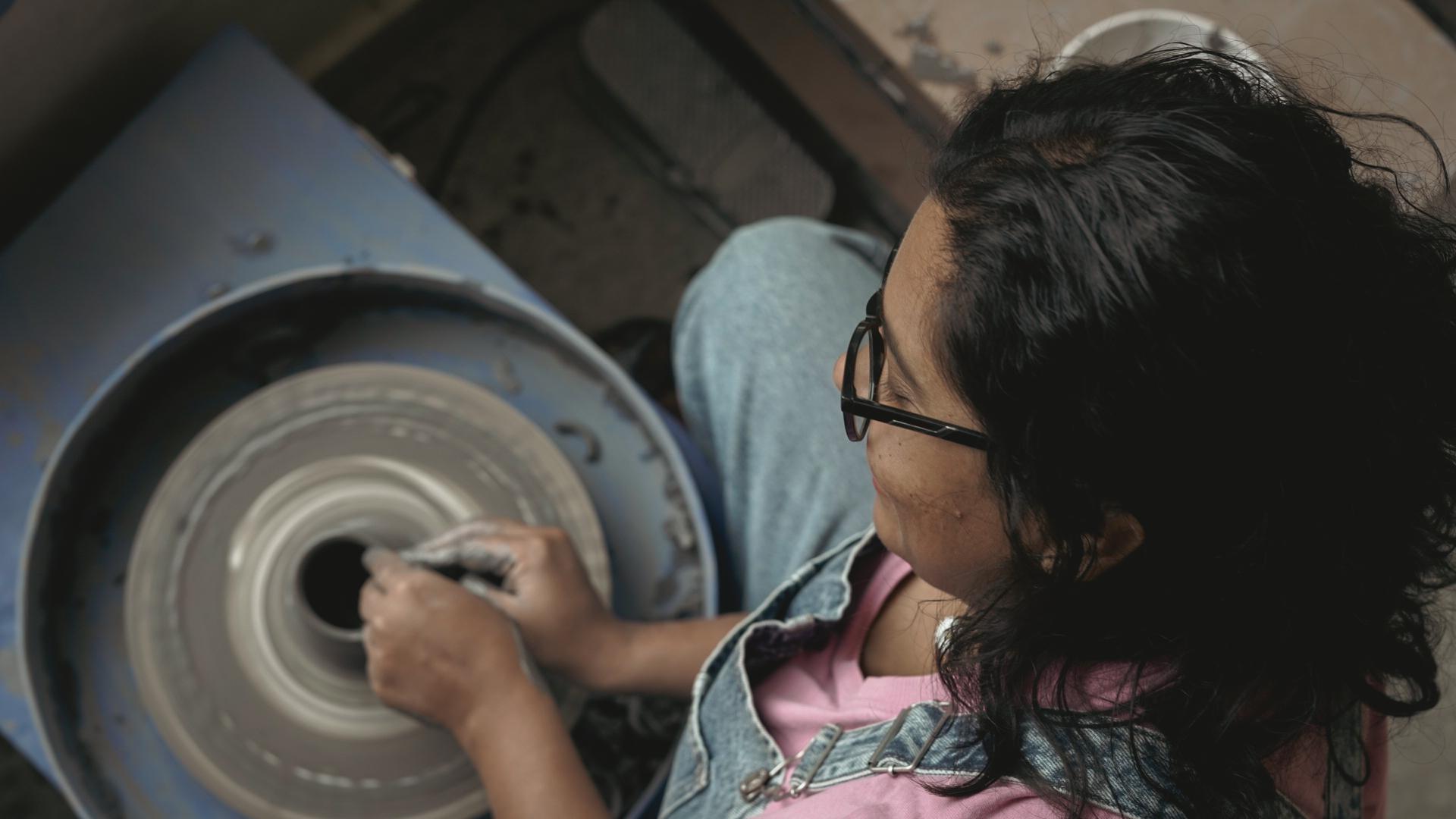 Top-down view of a potter shaping clay, hands cupped around the wall