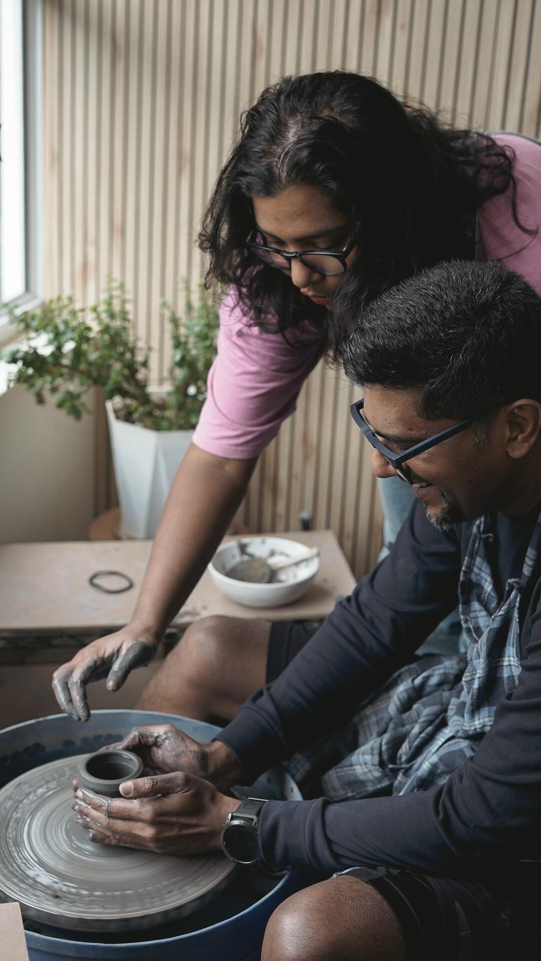 Mita guiding a student at the pottery wheel