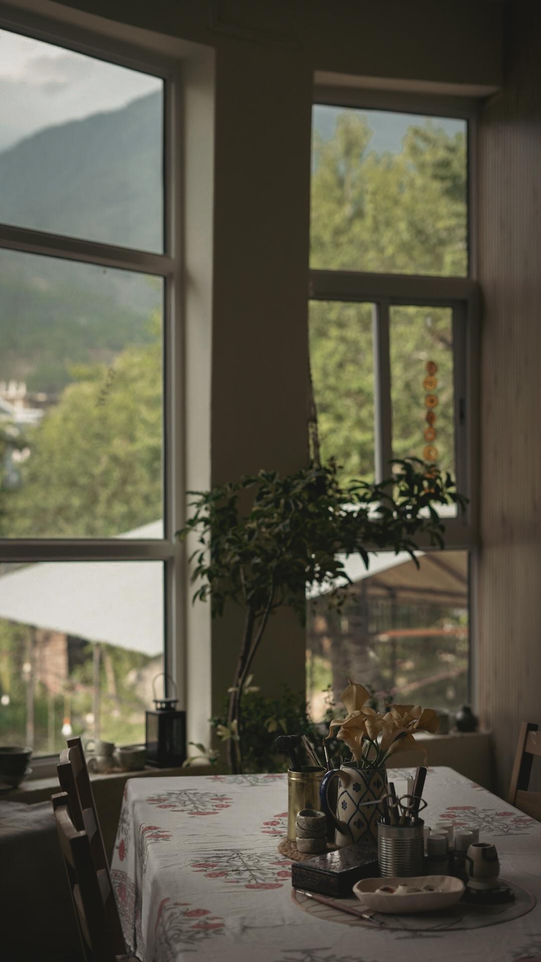 The studio table with tools laid out and the Dhauladhar range through the window