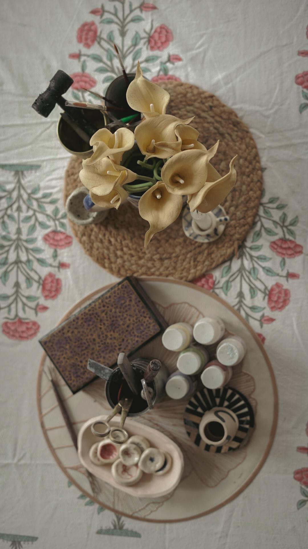 Flat-lay of pottery tools, lilies, and glaze bottles