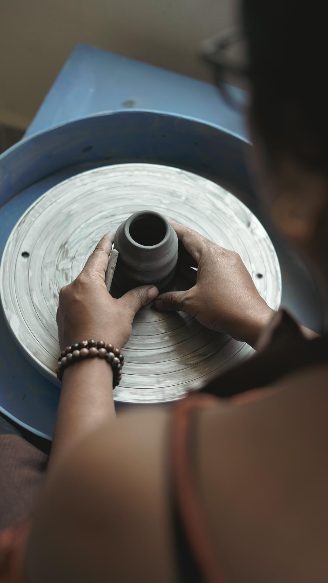 Potter refining vessel shape with a wooden rib tool