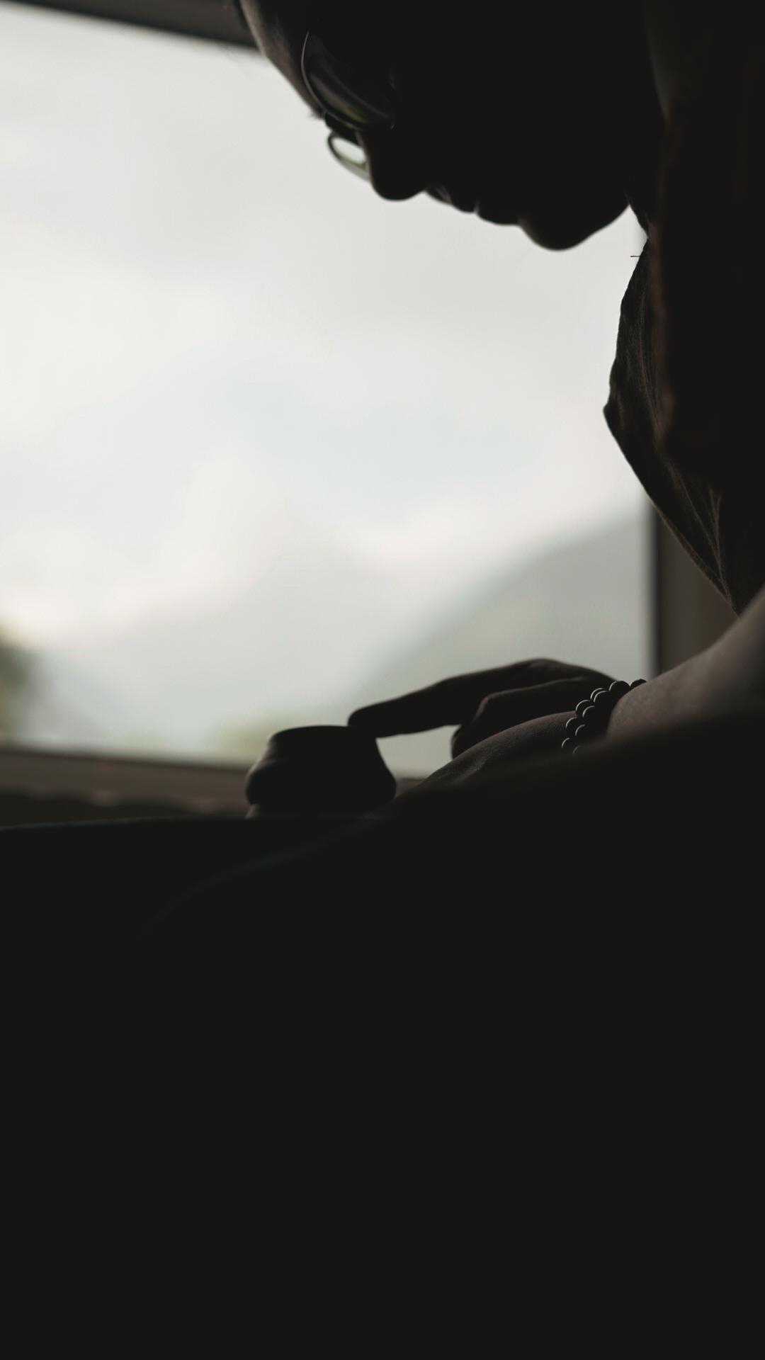 Silhouette of potter shaping a vessel rim against misty mountains