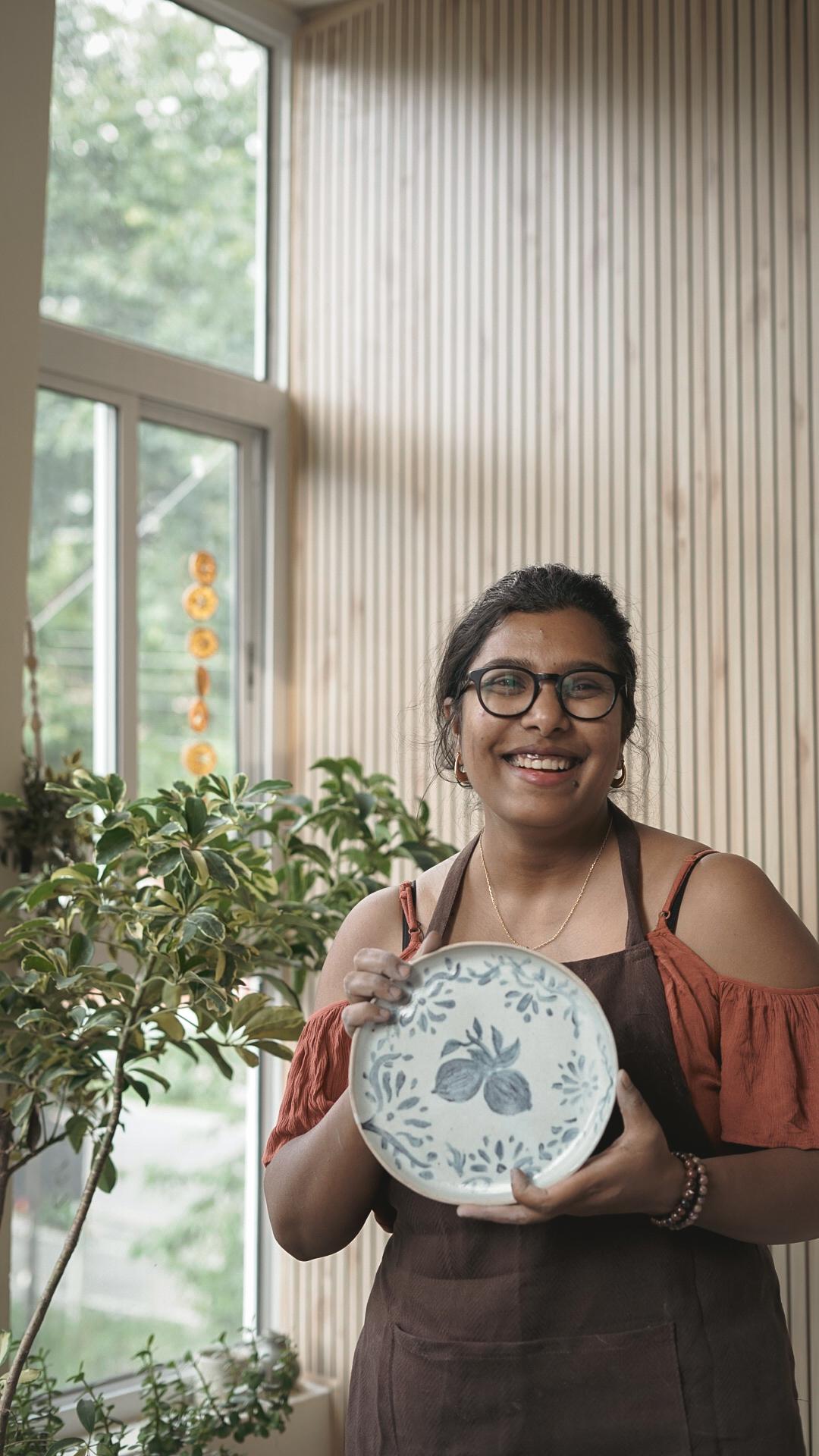 Madhumita smiling joyfully, holding one of her ceramic pieces