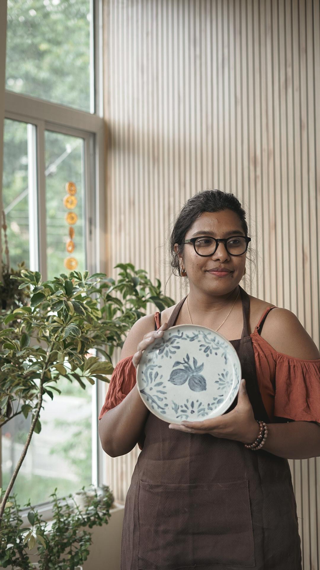 Potter presenting a hand-painted botanical plate