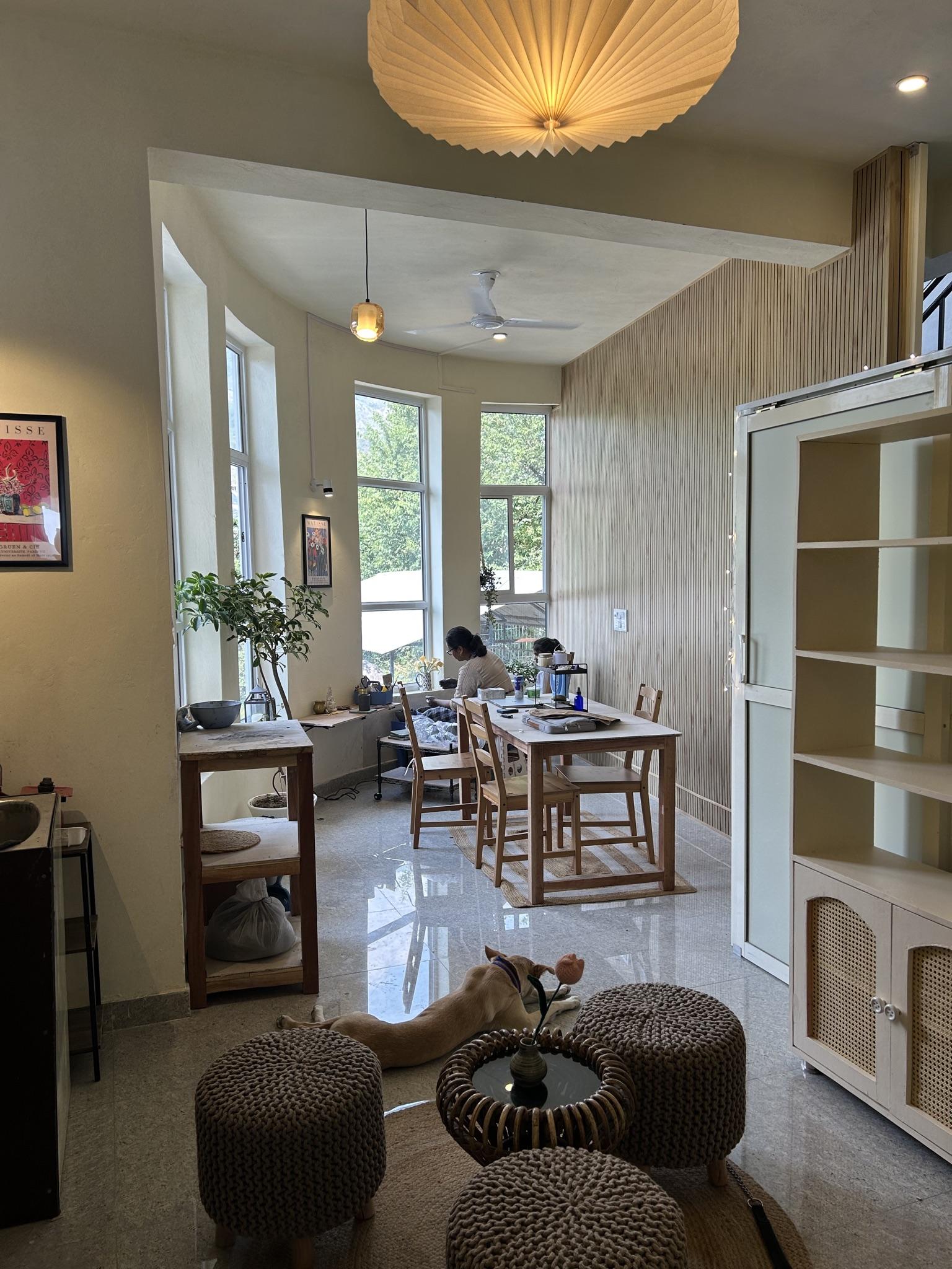 The studio interior with warm pendant light and Mita working at her table