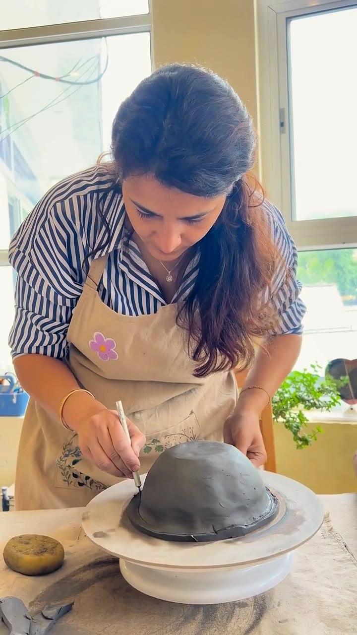 Madhumita carving fine lines into a dark clay dome turning on a banding wheel