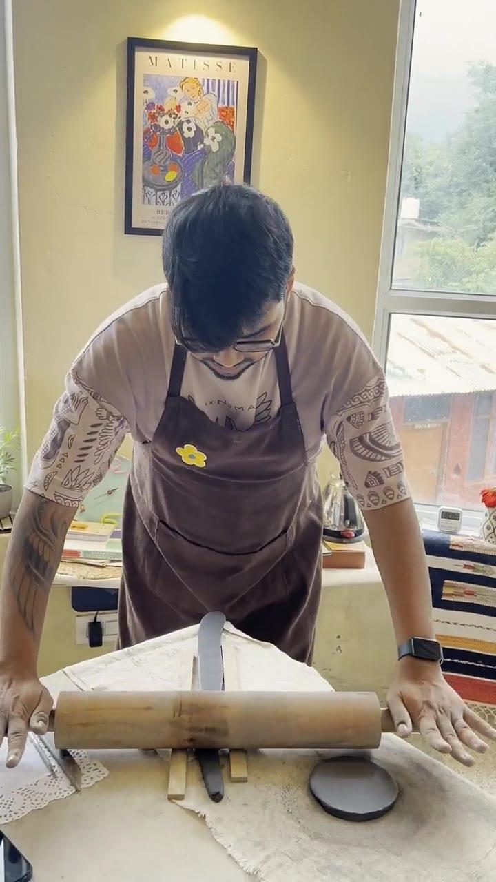 A slab of clay being smoothed flat with a rib before a leaf is pressed into it