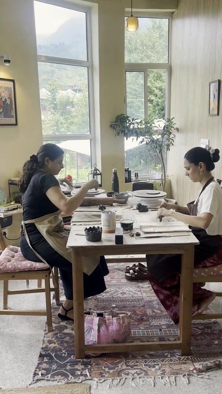 The studio's long table with the Dhauladhar range framed in the window behind it