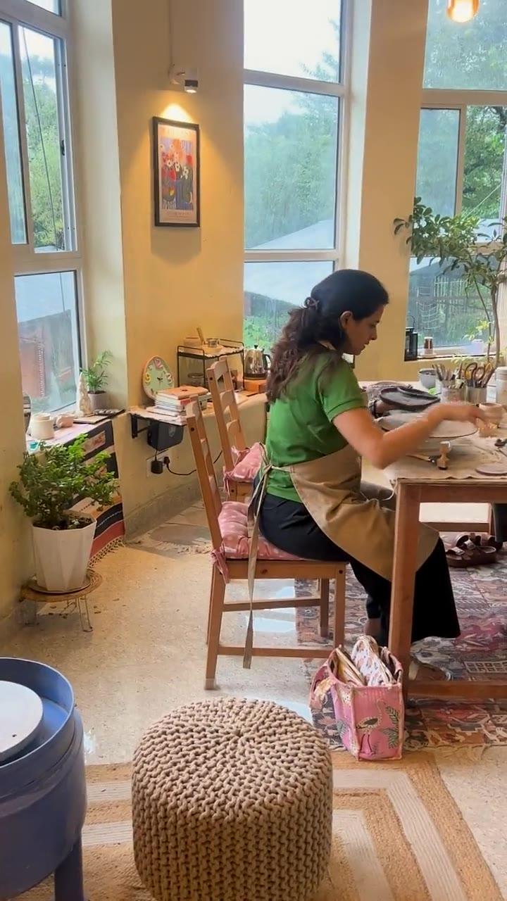 Madhumita working clay alone at the long studio table by the window