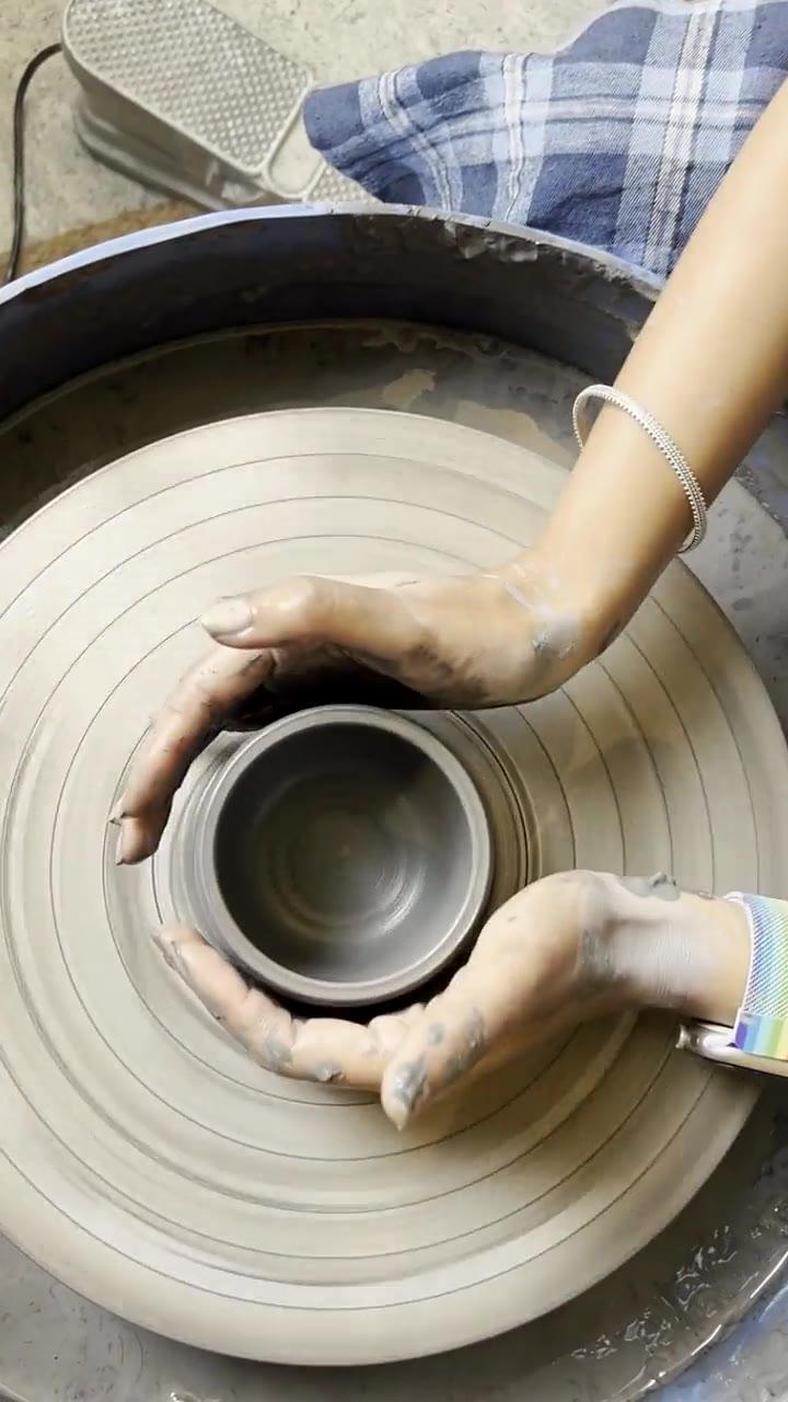 Hands steadying a spinning bowl on the potter's wheel, seen from above