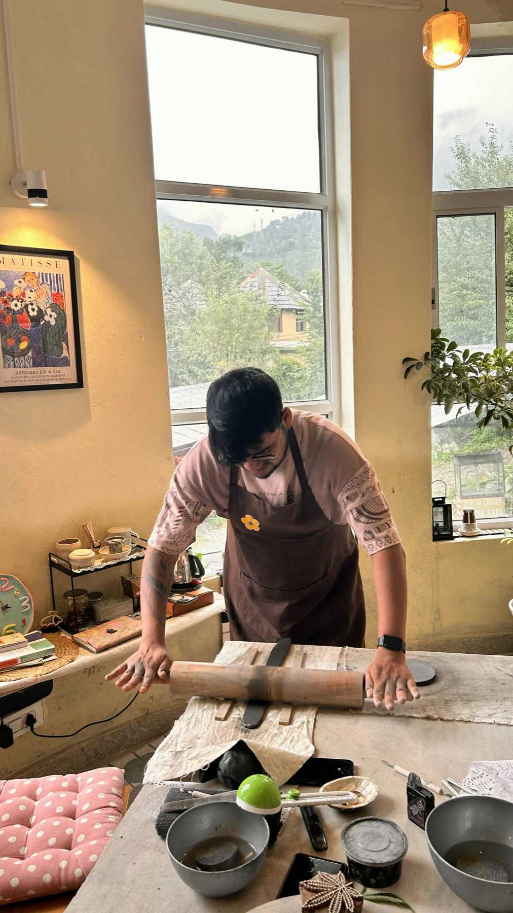 A guest working clay at the window table with the hills visible through the glass