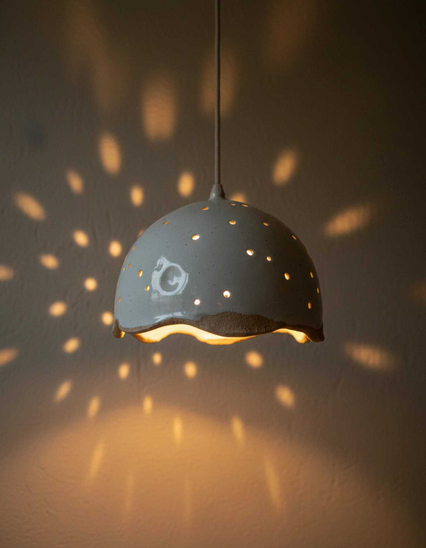 Illustration of a pierced white ceramic pendant lampshade casting dots of light across a wall