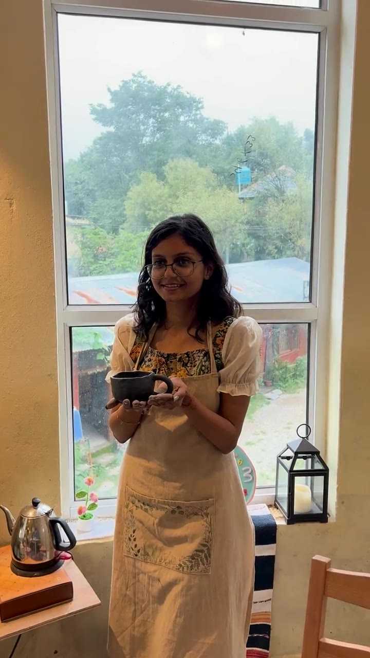 A guest holding the dark mug she made, at the studio window