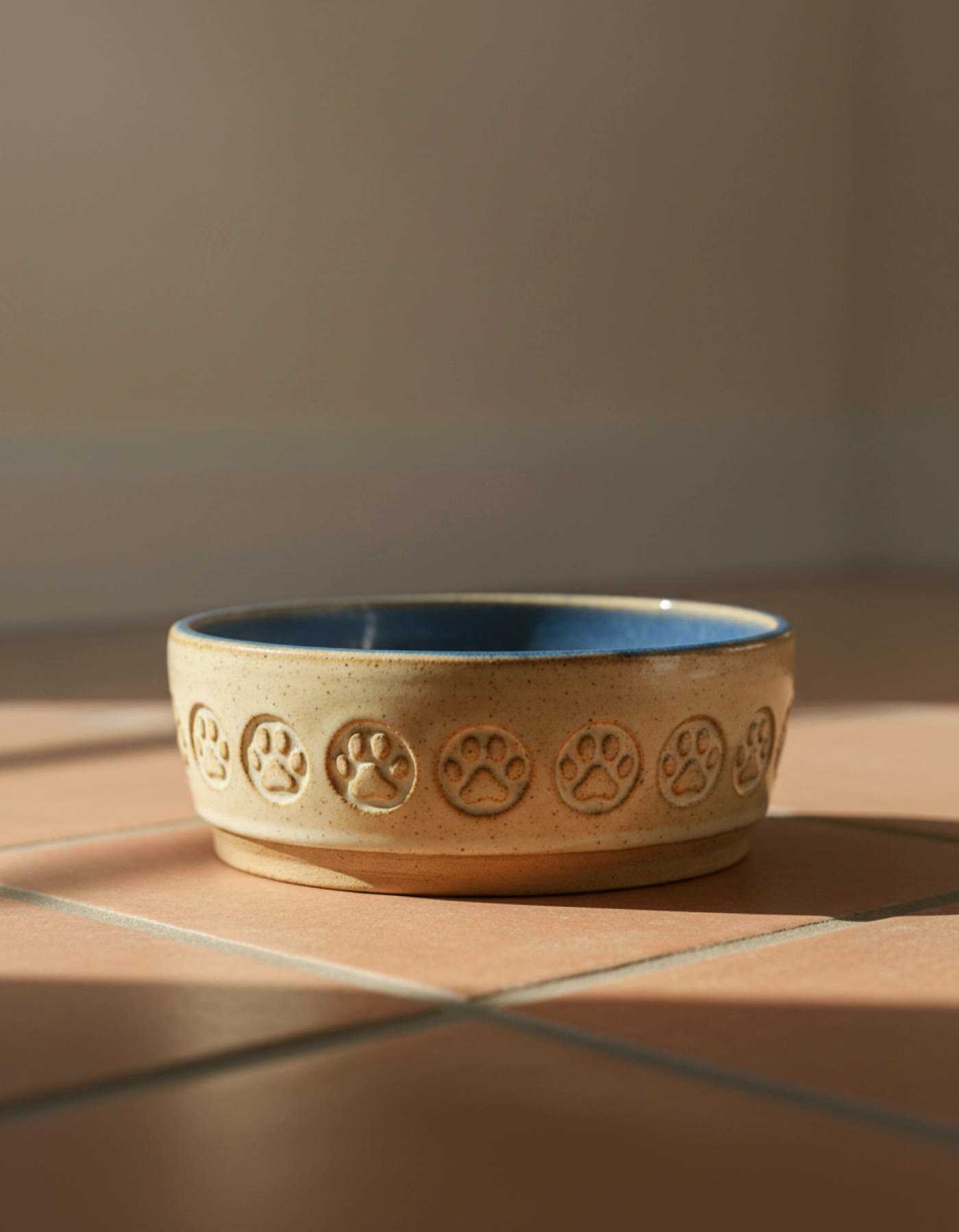 Illustration of a heavy cream pet bowl with paw prints pressed around the side and a blue inside