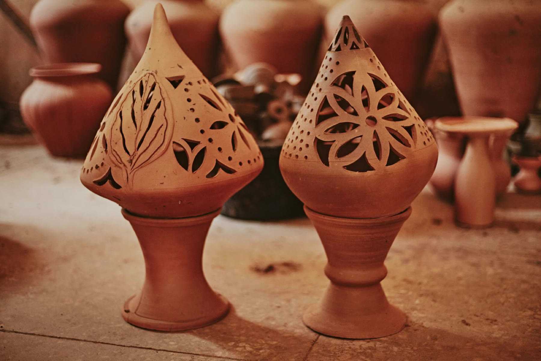 Two terracotta lanterns carved with pierced floral patterns