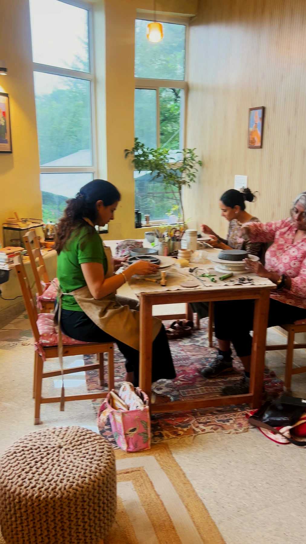Three people working clay side by side at the studio table