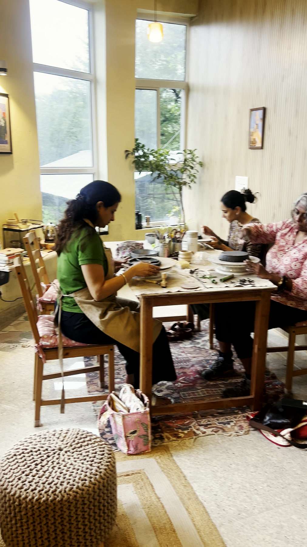 Hands shaping clay side by side at the long table