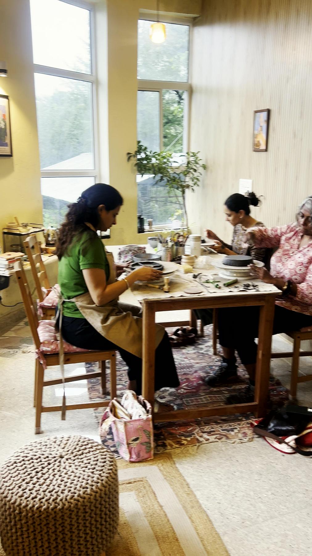 Hands shaping clay side by side at the studio's shared table