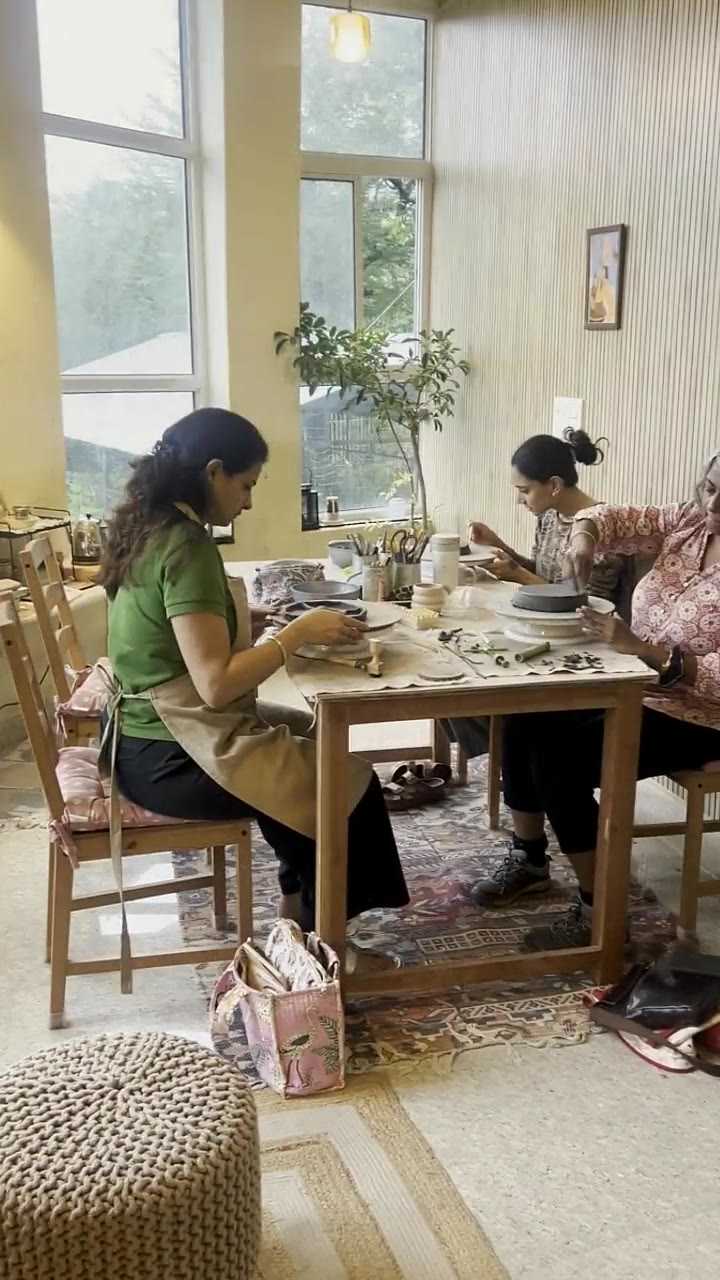 Three people working clay side by side at the studio table