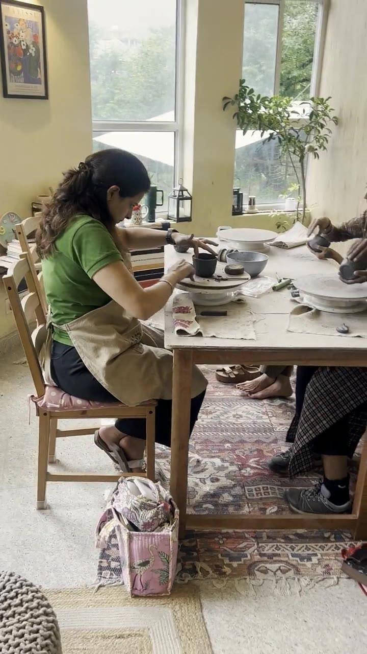 Several people hand-building at the studio's long table, mid-afternoon