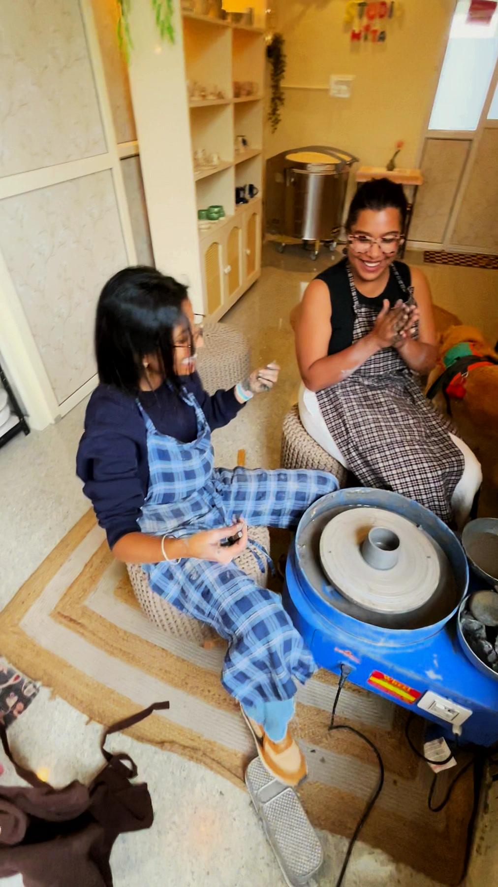 Two people laughing together at the wheel, one steadying the other's hands