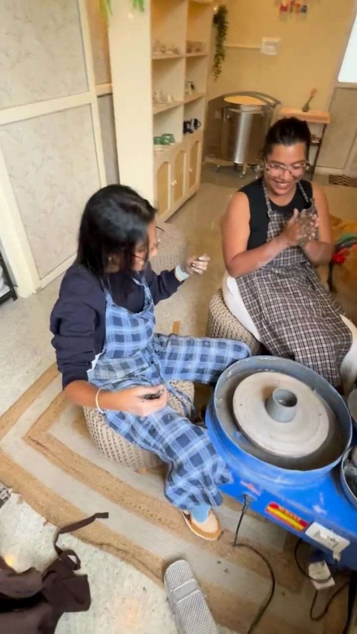 Two people laughing together at the wheel, one steadying the others hands