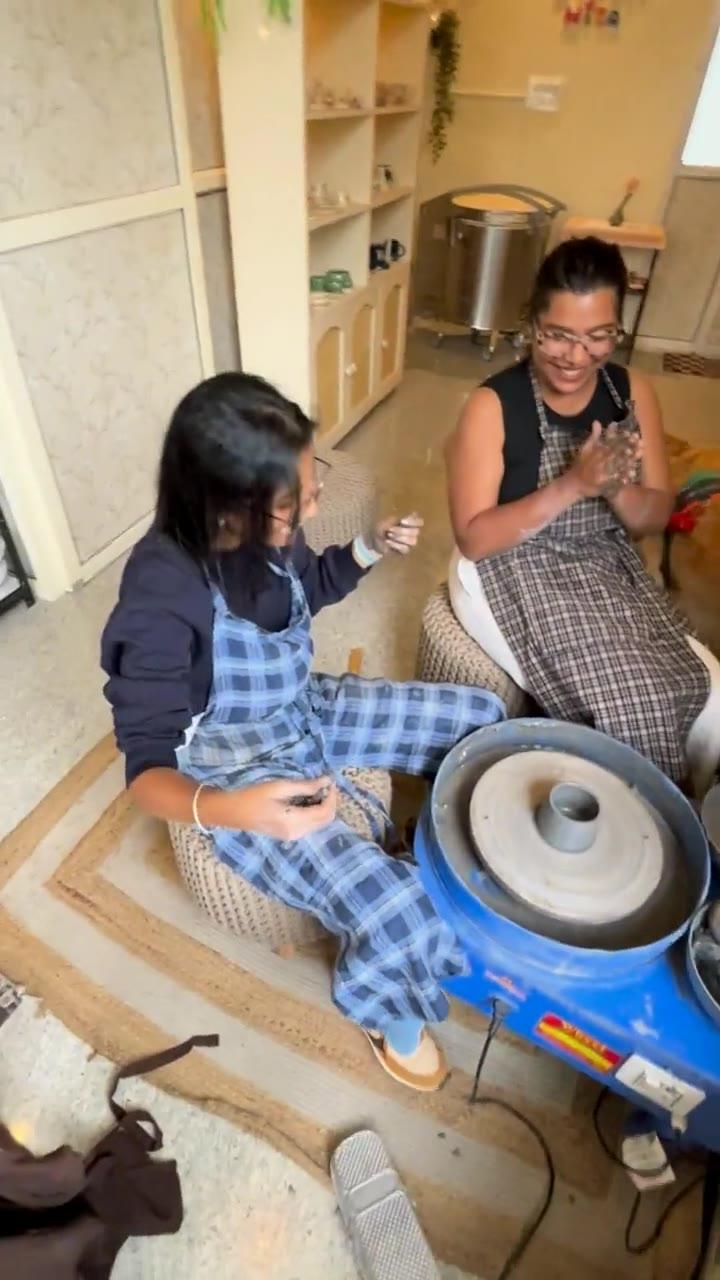 Two people laughing together at the wheel, one steadying the other's hands
